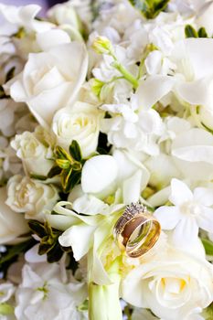 Wedding rings sit on a bride's bouquet during a wedding day ceremony.