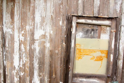 An old building with a peeling paint wood texture and a very old door on a shed or barn creates an abstract background image.