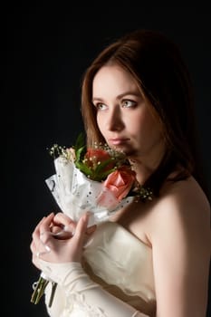 Portrait of an attractive young woman bride with bouquet on black background