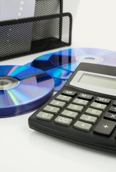 Office supplies, calculator, compact discs on white desk