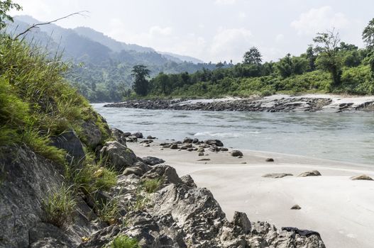 river in sun koshi, nepal with forest and small buildings