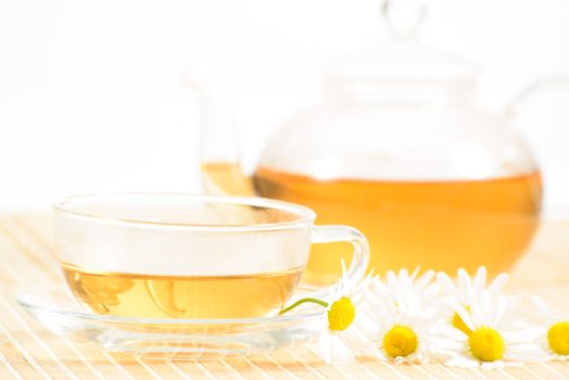 A teacup and a teapot with herbal chamomile tea