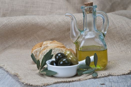 Olive oil with green olives and bread on a wooden surface