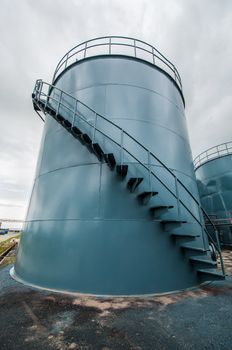  Vertical picture of  storage tanks and ladder on cloudy background