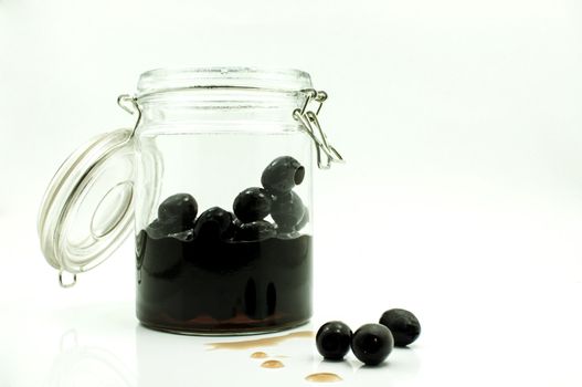 pickled black olives in glass bottle on a white background
