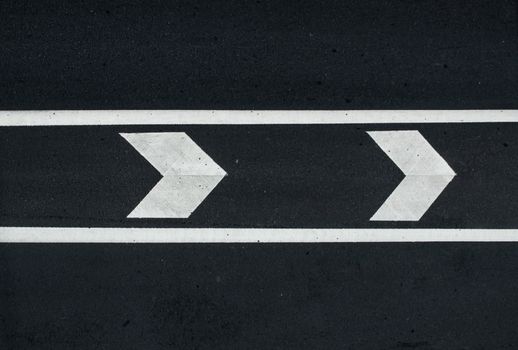 road marking: white arrows and line on the dark asphalt road.