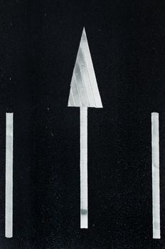road marking: white arrows and rectangles on the dark asphalt road.