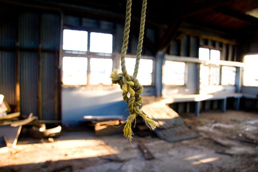 A rope dangles from the rafters at an old rundown warehouse building.