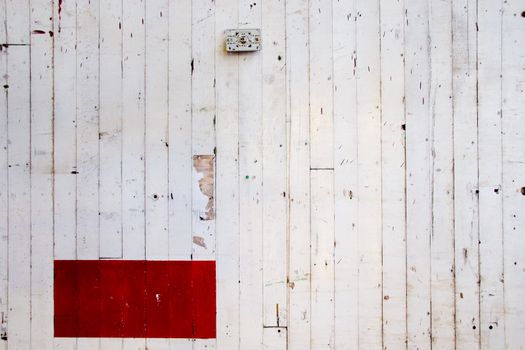 A very simple photo of a white wall with lines in the paint and a red rectangle of color.