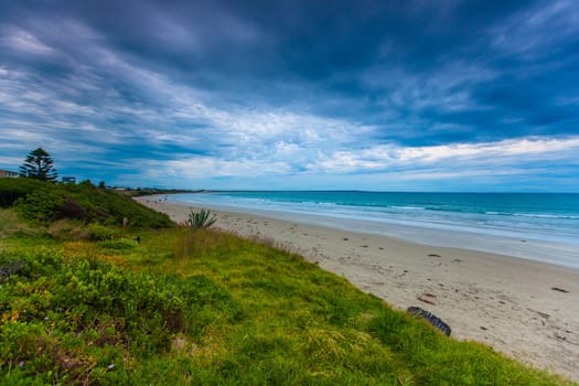 Evening on the beach in Port Fairy, VIC. Calm ocean with dramatic cloud over the sand dune cover in vegetation.