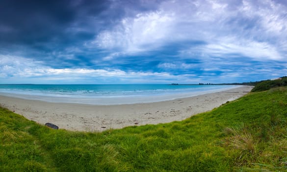 Evening on the beach in Port Fairy, VIC. Calm ocean with dramatic cloud over the sand dune cover in vegetation.