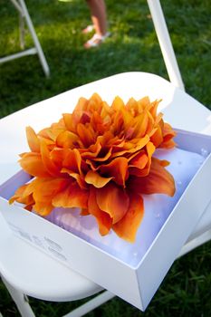A bright flower attached to a white pillow for a ring bearer to carry at a wedding ceremony.