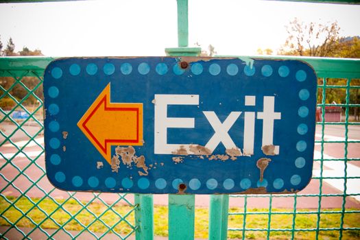 An arrow on a sign that says exit points to the left in an artsy photograph that is unique and interesting.