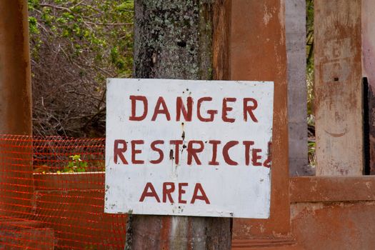 A hand written sign by an old home that is falling apart and crumbling to the ground.