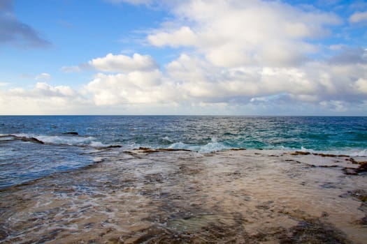 A beautiful beach with nobody in the scene as well as a dynamic sky and nice turquoise and blue tones throughout in color.