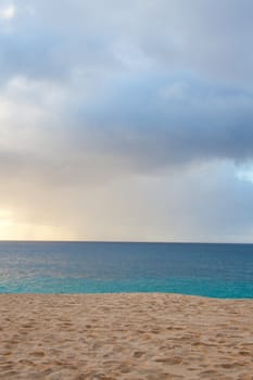 A beautiful beach with nobody in the scene as well as a dynamic sky and nice turquoise and blue tones throughout in color.