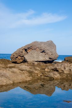 A large rock is reflected in a tide pool along the northshore of oahu hawaii.