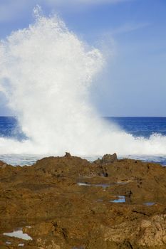 Large white waves crash together along the north shore of oahu hawaii during the daytime.