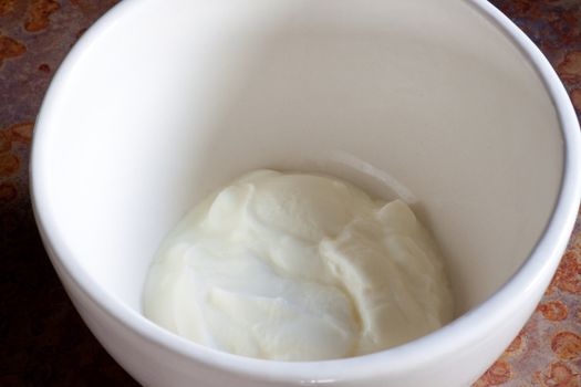 Plain white yogurt sits in a large bowl waiting for toppings to complete this healthy nutritious breakfast meal.