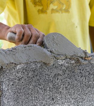 Bricklayer putting down another row of bricks in site