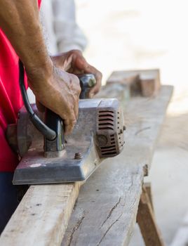 Carpenter working with electric planer  in his workshop, close up on the tool with hands
