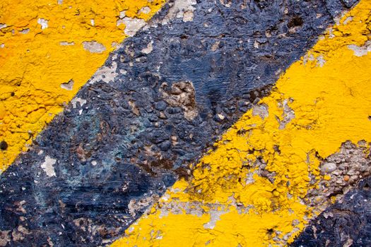 A black and yellow old wall is striped for warning or caution to create an abstract texture of a rubble decaying building wall.