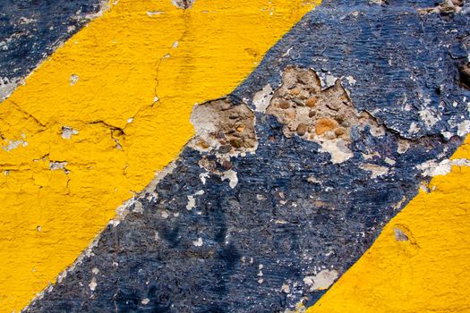 A black and yellow old wall is striped for warning or caution to create an abstract texture of a rubble decaying building wall.