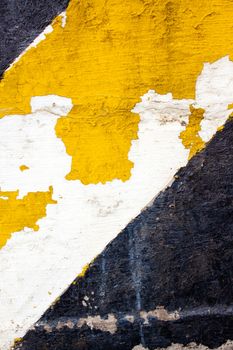 A black and yellow old wall is striped for warning or caution to create an abstract texture of a rubble decaying building wall.