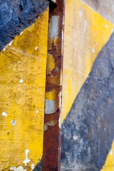 A black and yellow old wall is striped for warning or caution to create an abstract texture of a rubble decaying building wall.