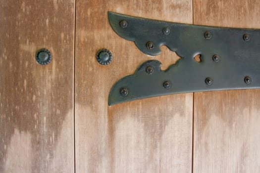 An old piece of hardware is mounted to a very old wooden door.