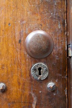 A very old door handle and lock on a vintage wooden building with craftsmanship and originality.