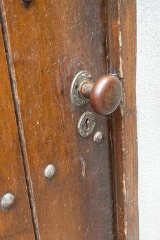 A very old door handle and lock on a vintage wooden building with craftsmanship and originality.