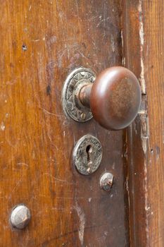 A very old door handle and lock on a vintage wooden building with craftsmanship and originality.