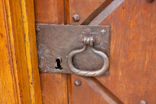 A very old door handle and lock on a vintage wooden building with craftsmanship and originality.