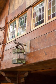 A vintage lantern light hangs outside of an old wooden craftsman-style home.