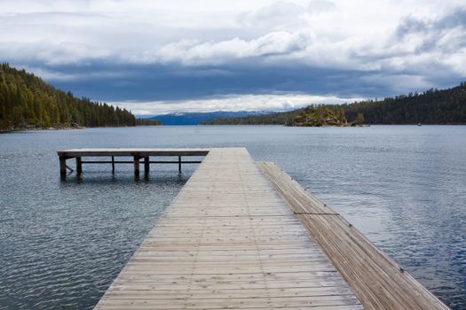 Views of Lake Tahoe in California with crystal clear water, snow on the ground, and mountains in the background.