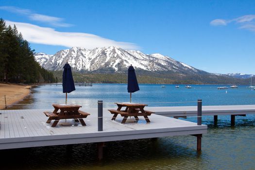 Views of Lake Tahoe in California with crystal clear water, snow on the ground, and mountains in the background.