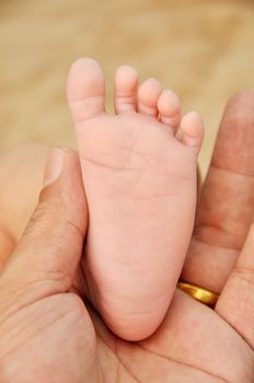 father holding baby foot on his palm