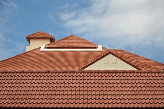 View of red roof tiles and cloudy sky on the background.