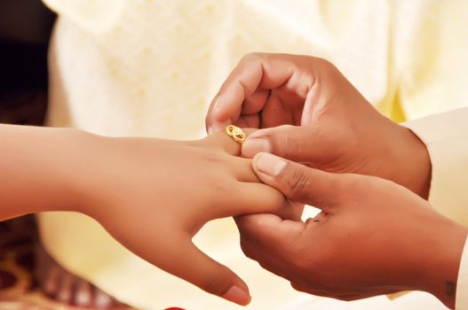 Groom wears a diamond ring onto the brides hand on wedding ceremony