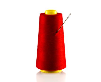 red bobbin with thread and needle isolated on white
