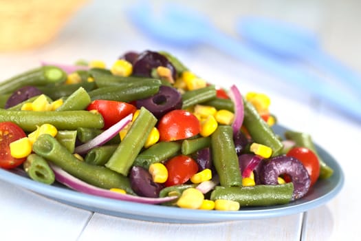 Fresh vegetarian green bean salad with cherry tomatoes, corn, black olives and onion (Selective Focus, Focus one third into the salad)