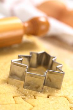 Baking Christmas Cookies: Cookie cutter on rolled out sugar or butter cookie dough with rolling pin and eggs in the back (Selective Focus, Focus on the lower edge of the cookie cutter) 