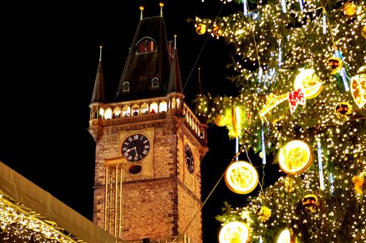 Christmas & New Year Eve illumination and atmosphere on Old Town Square in Prague, with Prague Astronomical Clock on the background, with christmas tree's lights, by night