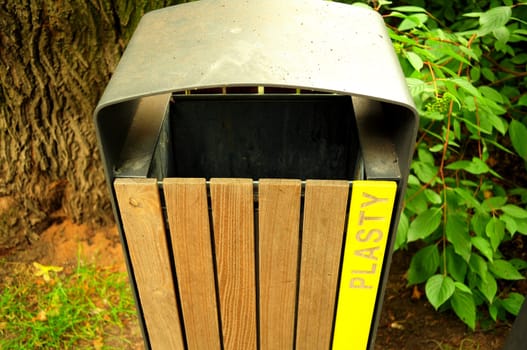 Bin for plastic garbage in the park, on a background of trees and shrubs