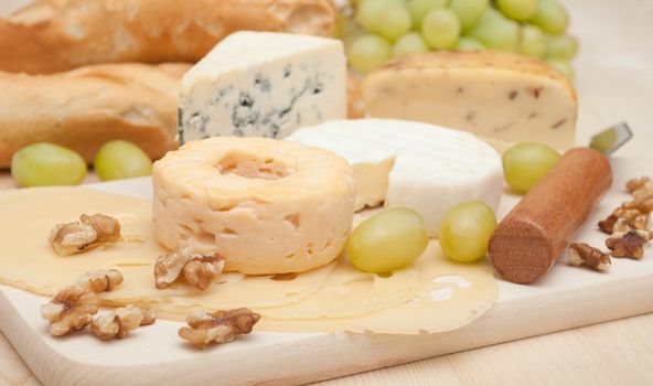 Various Types of Cheese and Grapes on Wooden Chopping Board 