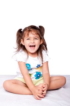 Cute happy smiling laughing toddler girl sitting on bed.