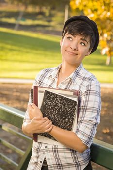 Outdoor Portrait of a Pretty Mixed Race Female Student Holding Books Looking Away.