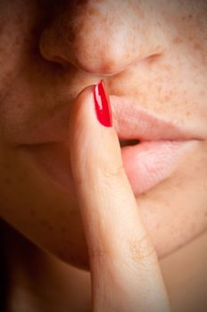 Closeup of a woman with her finger over her mouth