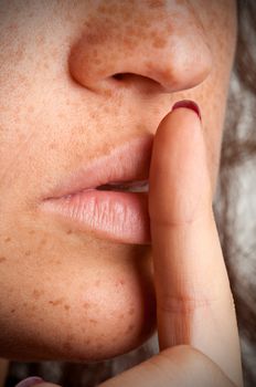 Closeup of a woman with her finger over her mouth